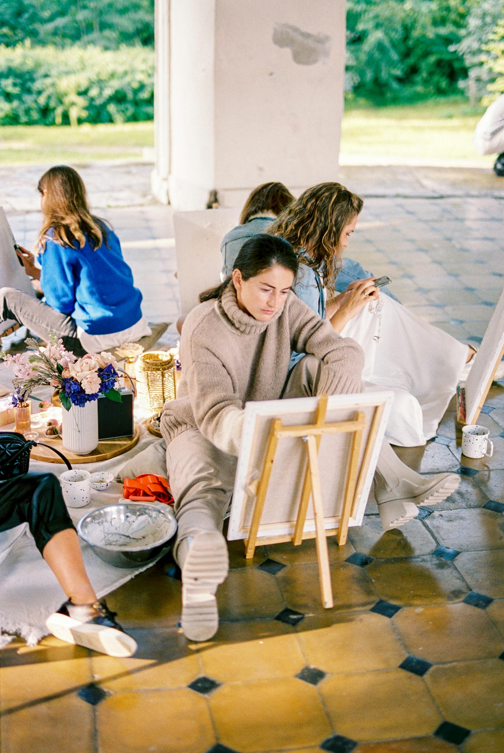 A group of women engaged in painting and creating art in an outdoor workshop.